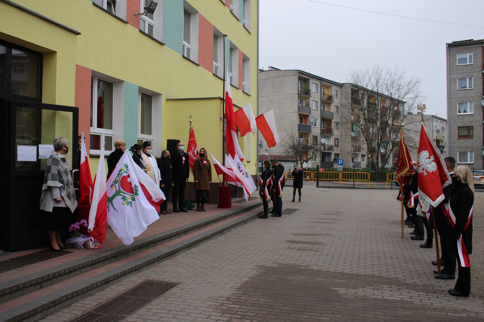 Zdjęcie przedstawia ludzi, którzy biorą udział w uroczystości nadania imienia szkole. 