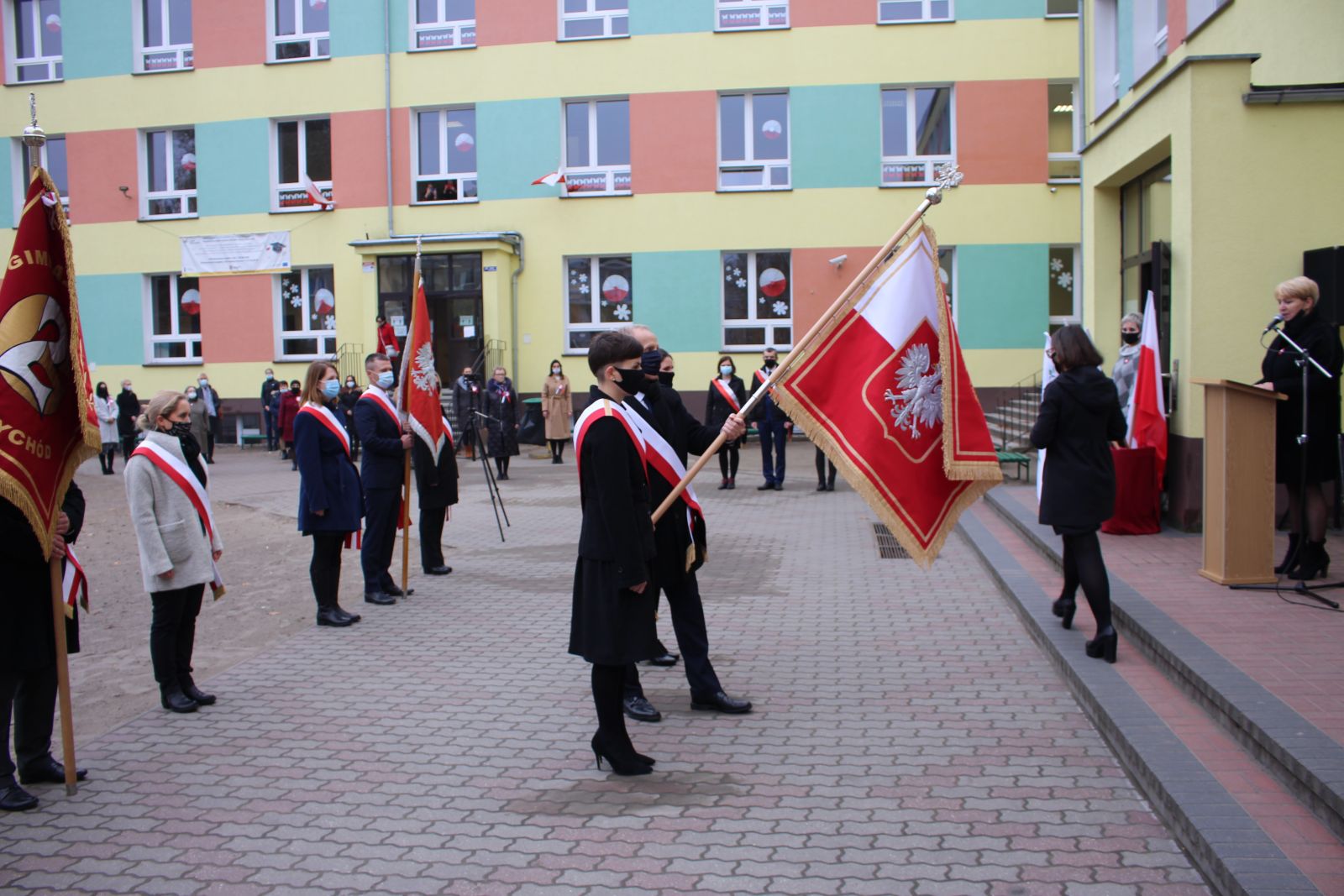 Zdjęcie przedstawia ludzi, którzy biorą udział w uroczystości nadania imienia szkole. 