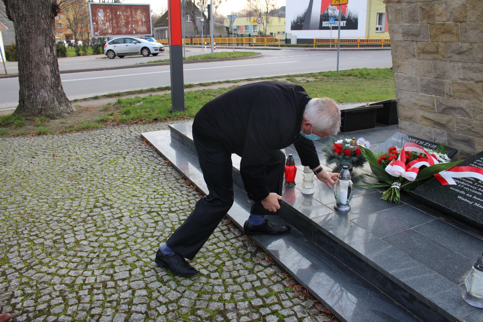 Zdjęcie przedstawia Ryszarda Suleja, który składa znicz pod Pomnikiem Powstańców Wielkopolskich
